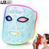 A woman is applying an 8-color LED light therapy face mask to her face.
