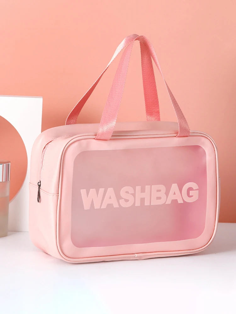 A pink transparent cosmetic storage bag with pink straps and the word WASHBAG printed on it.