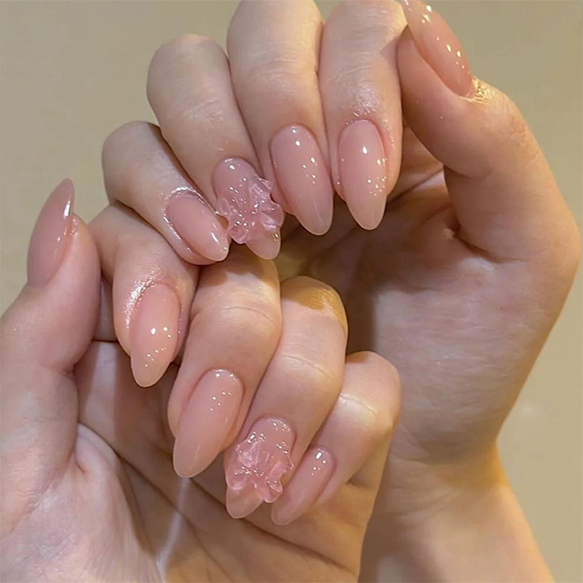 A close-up of a hand displaying 24 pink heart pearl press-on fake nails on fingers.