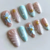 A collection of 24 press-on nails featuring a soft pink and blue gradient with delicate white flowers and gold accents.