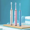 Three ultrasonic electric toothbrushes in white, pink, and blue are displayed on a light surface.