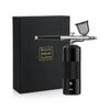 A black box and a silver beauty airbrush system with a clear nozzle are displayed on a white surface.