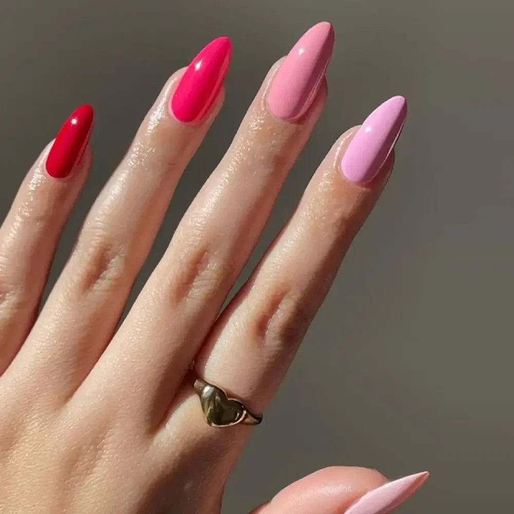 A hand displaying 24 press-on false nails with a French wavy design in shades of pink and magenta.