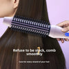 A hand holds a pink heated curling iron brush with black teeth, positioned near dark hair.