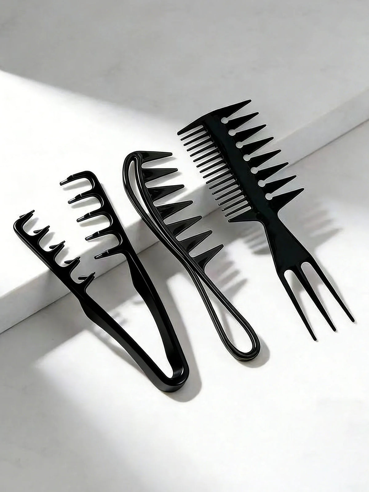A set of black men's salon hair styling combs, including a fine-toothed comb and a wide-toothed comb, displayed on a white su