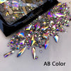 A collection of iridescent and clear glass rhinestones in an AB color scattered on a white surface.