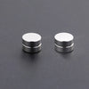 A pair of silver crystal magnetic stud earrings for men displayed on a dark gray surface.
