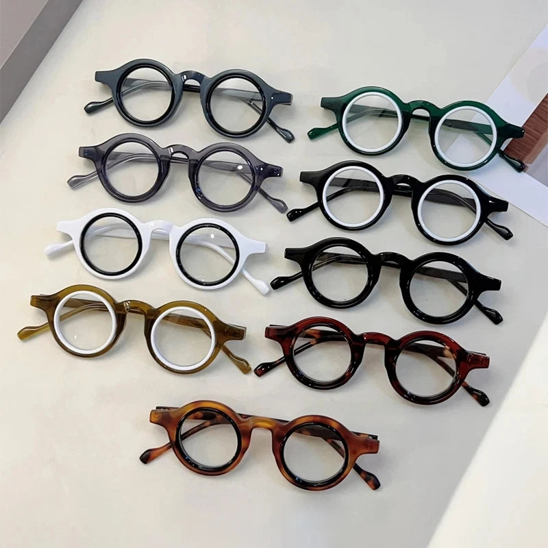 Collection de lunettes de lecture claires réglables, différentes montures et couleurs, disposées sur une surface blanche.