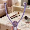 A hand holds a purple precision spring-action facial hair remover with attached brushes on a white surface.