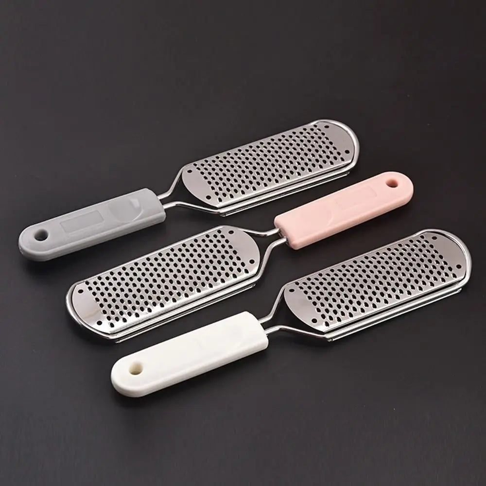 Three stainless steel foot files with plastic handles are displayed on a dark surface.