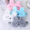 Una colección de lindas máscaras de ojos de conejito de peluche en rosa, azul y gris exhibidas sobre una superficie blanca.