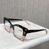 A pair of tortoiseshell reading glasses with pink frames resting on a white surface.