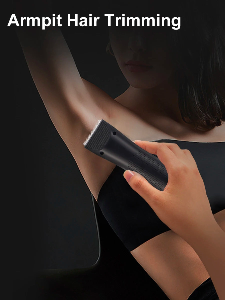 A hand holds a black electric hair trimmer against a person's arm for hair trimming.