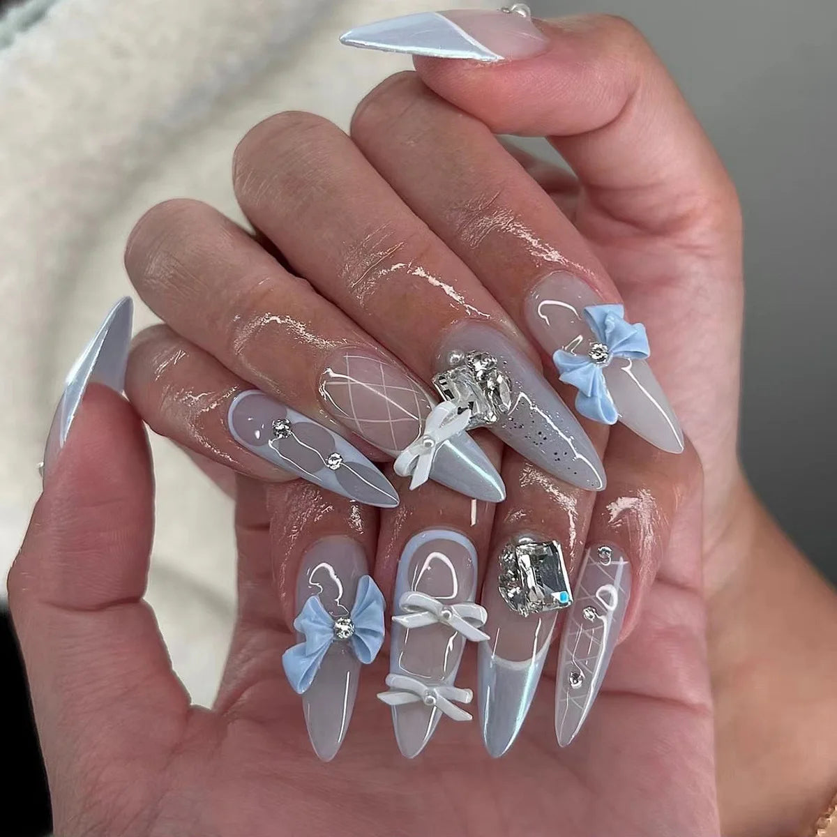 A hand displays 24 press-on fake nails with a light pink and white gradient finish and delicate pearl accents.