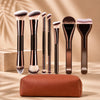 Un set de brochas de maquillaje profesionales de doble extremo en varios tonos, exhibidas sobre una superficie de madera.