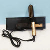 A black electric straightening comb with a gold handle rests on a black box.