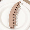 A beige silicone hair clip is shown resting on a white plate.