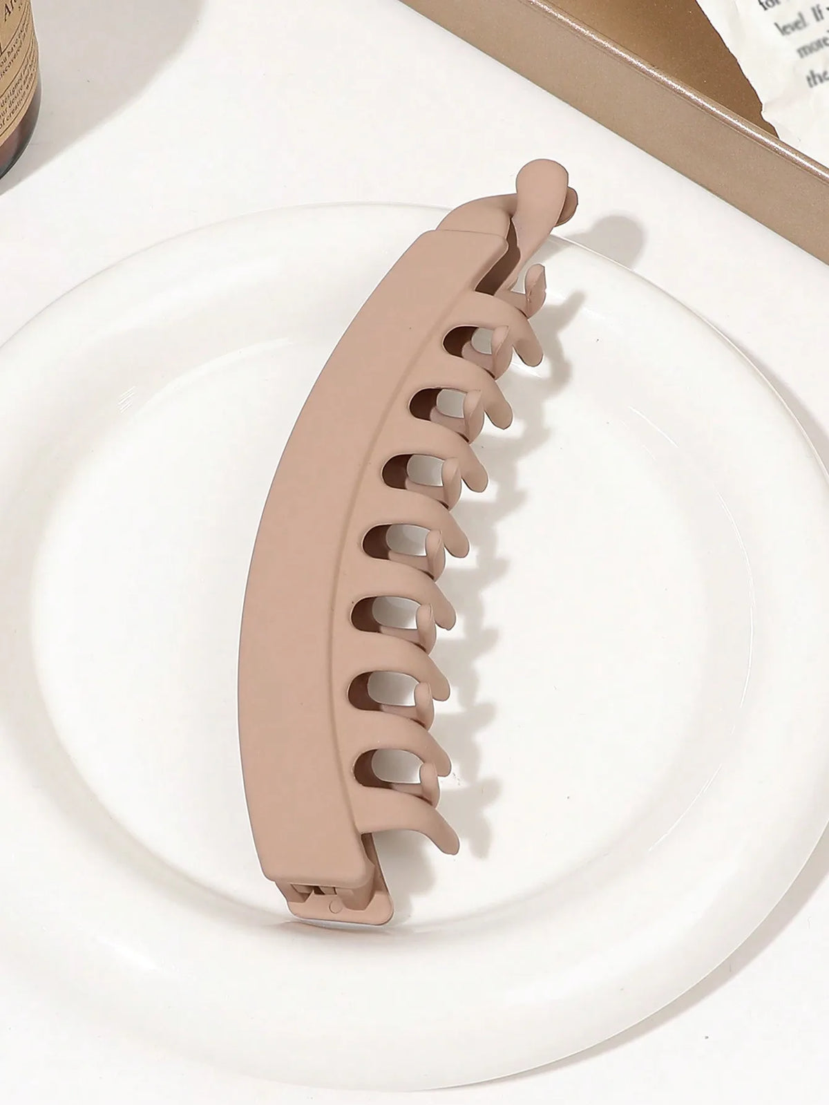 A beige silicone hair clip is shown resting on a white plate.