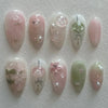 A collection of 24 press-on nails featuring pink and green floral designs on an almond shape.