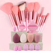 Una colección de 12 brochas de maquillaje profesionales en varios tonos rosa y nude, exhibidas en una caja gris claro.