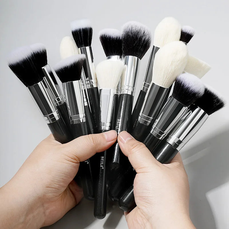 A hand holds a set of 30 professional makeup brushes with black and white bristles.
