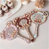 A set of three hand holding makeup mirrors with floral and heart designs on a white background.