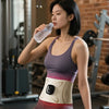 A woman wearing a purple EMS waist pulse massager device while exercising in a gym setting.