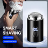 A close-up of a black electric shaver with a digital display showing 100 percent battery, being used for shaving.