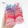 A hand holds a clear plastic bag containing 20 pink and purple air cushion beauty puffs.