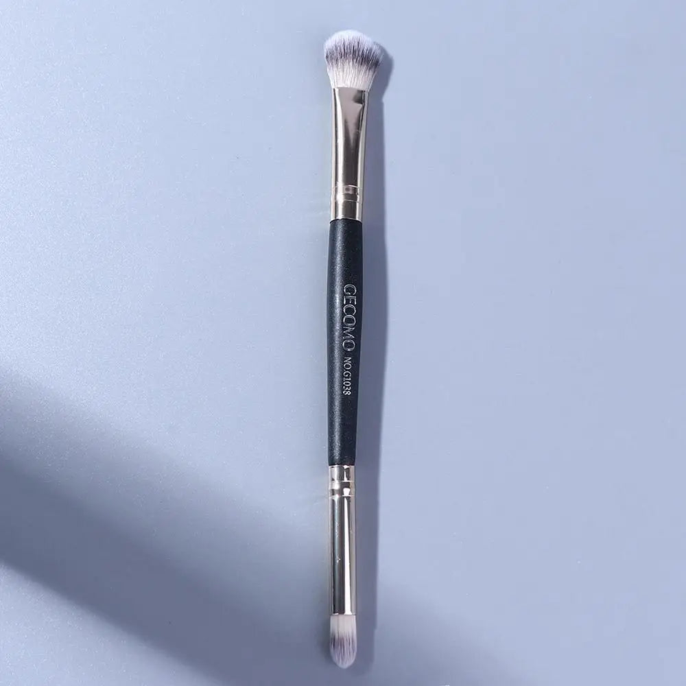 A long, double-ended eye shadow brush with a smudge tip and blending shader, shown vertically against a light gray background