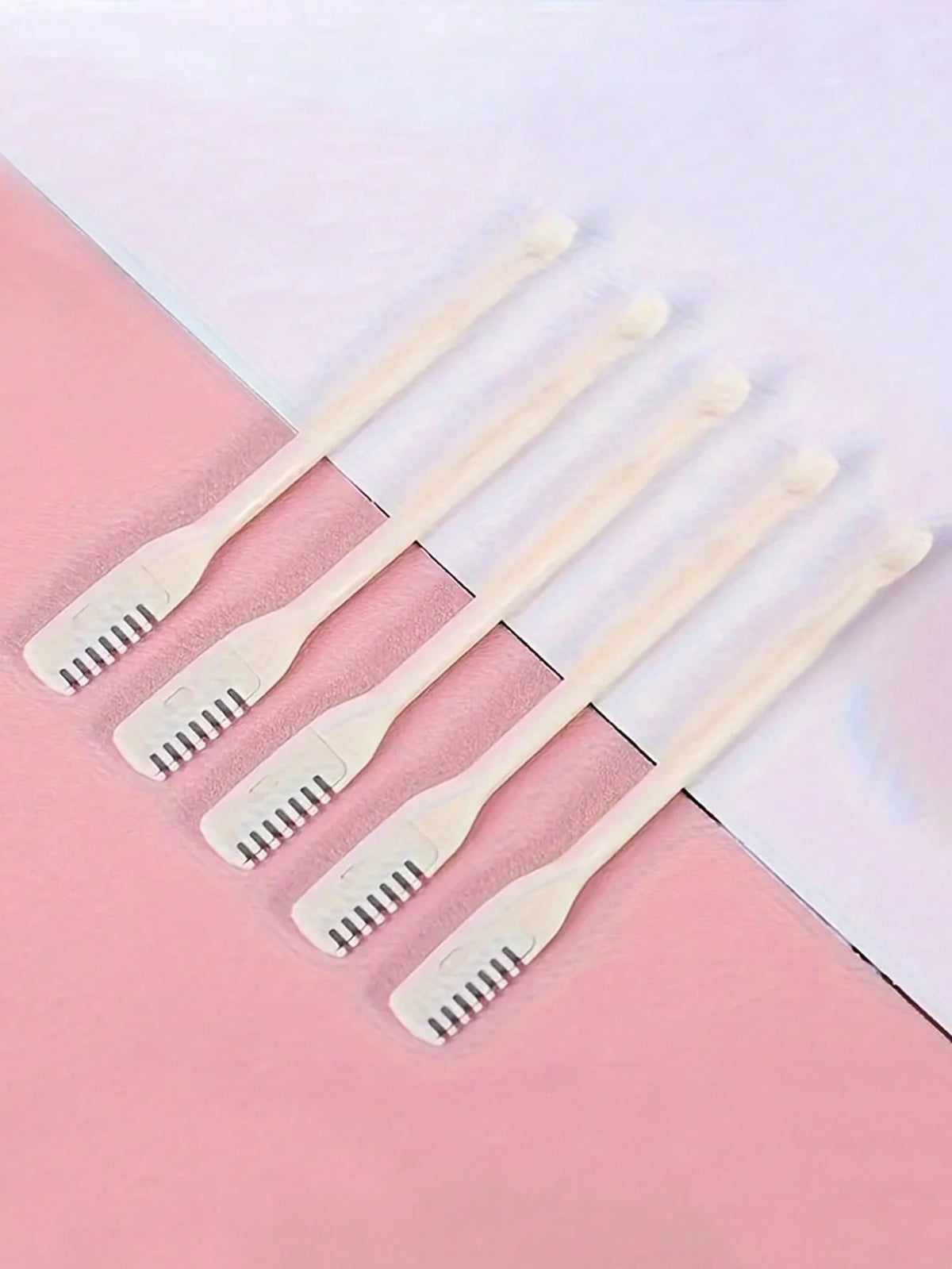 Five white double-headed manual nose hair trimmers arranged diagonally on a pink and white background.
