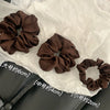 Collection de pinces à cheveux en satin de chiffon marron de différentes tailles, disposées sur du papier de soie blanc.