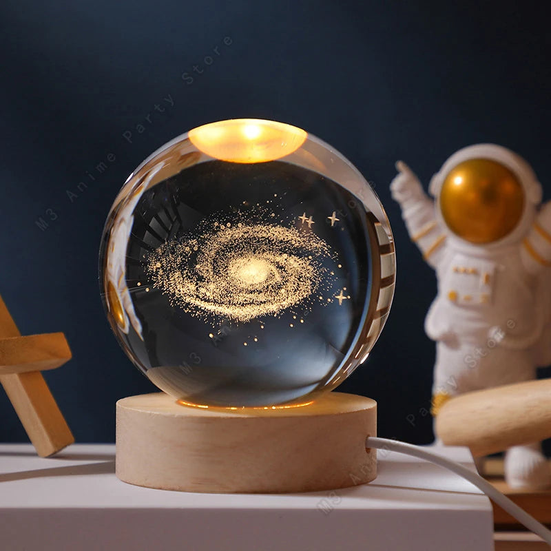 A glass crystal ball night light with a glowing orb resting on a wooden base.