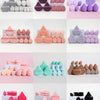 A collection of 12 makeup sponges in various shades of pink, purple, and gray arranged in rows.