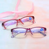 Pair of pink and purple retro style anti-blue light reading glasses with a pink ribbon in the background