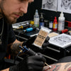 A person in black gloves is using a double round cotton tip on a precision wooden swab for a cosmetic or medical procedure.