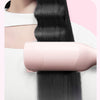 A pink professional double barrel curling iron is shown holding a long, dark hair strand.