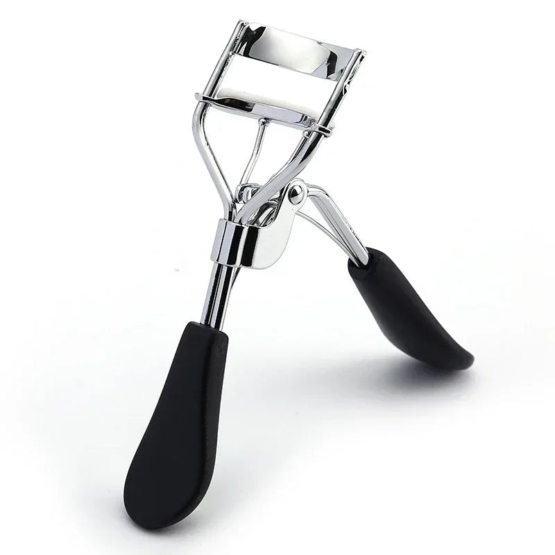 A silver professional eyelash curler with black rubber grips shown against a white background.