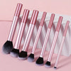 A set of seven professional makeup brushes with rose gold handles and black bristles displayed on a white box.