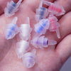 Una mano sostiene varios tapones para los oídos de silicona reutilizables en varios colores, incluyendo rosa, azul y morado.