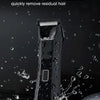 A black body grooming hair trimmer is being rinsed under a faucet to remove residual hair.