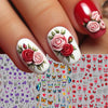 A close-up of a hand displaying various pink and red flower and butterfly nail stickers on an acrylic nail.