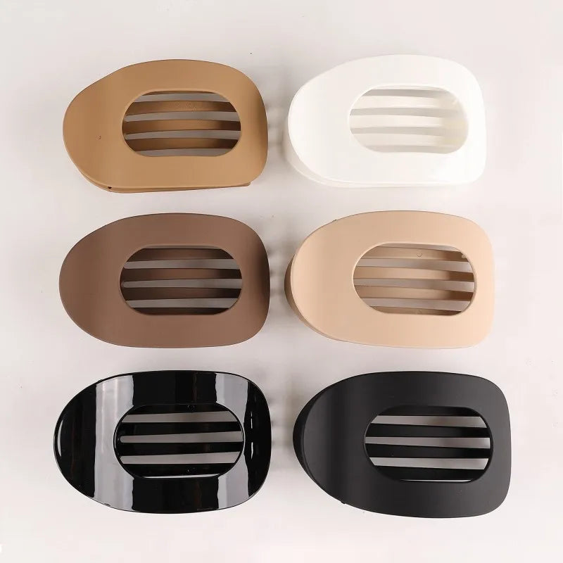 A set of four oval flat hair clips in beige, white, brown, and black finishes.