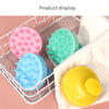 Présentation de brosses nettoyantes pour cuir chevelu en silicone, roses, vertes et bleues, dans un panier de fil blanc.