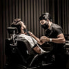 A man is using a professional cordless hair clipper for men and beard trimmer on another person's face.