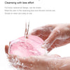 A hand is using a pink, waterproof facial cleansing brush to cleanse the skin with water.