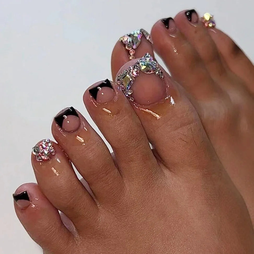 A close-up of a hand displaying press-on fake nails with short square French design featuring glitter and gold accents.