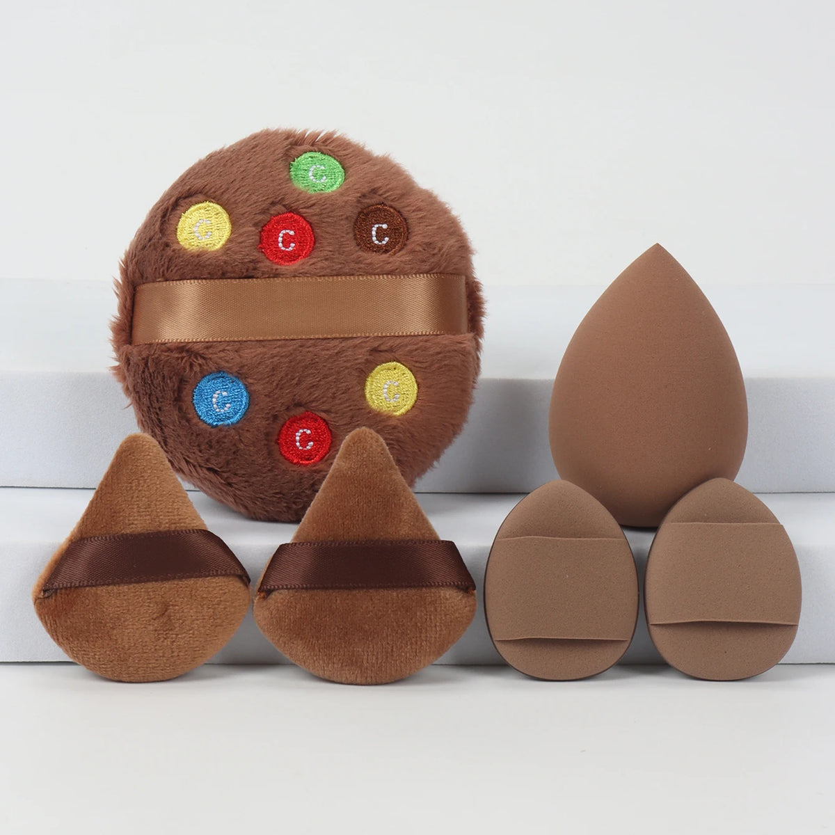 Un ensemble de puffs de poudre brune avec des points colorés brodés et des bandes brunes.