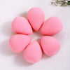 Six pink beauty egg puffs arranged in a circle on a white surface.