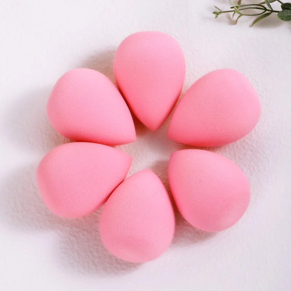 Six pink beauty egg puffs arranged in a circle on a white surface.